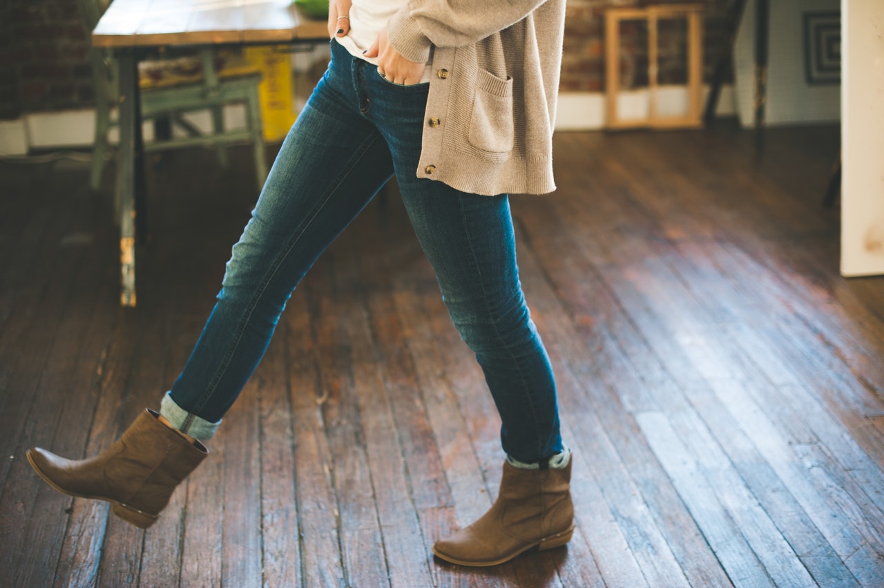 zoom sur les jambes d'une femme portant un jean des bottines basses et un gilet long beige